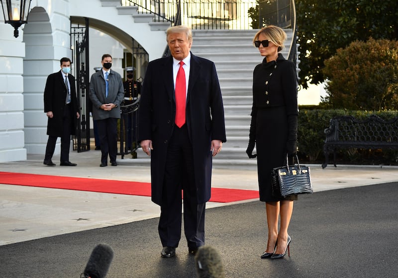 Outgoing US President Donald Trump and First Lady Melania Trump talk to the press as they depart the White House in Washington, DC, on January 20, 2021. Melania is holding a black Birkin bag.