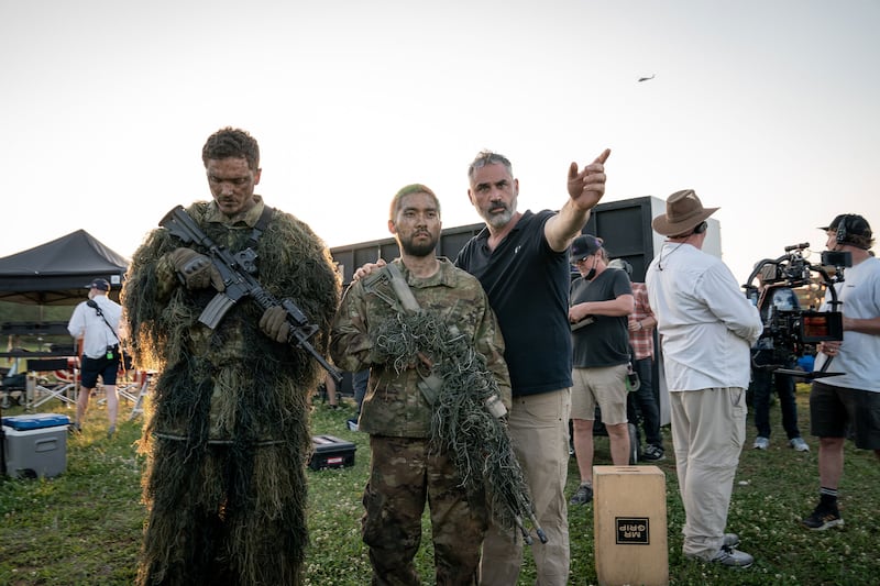 A behind the scenes picture of Alex Garland talking to actors on the set of Civil War